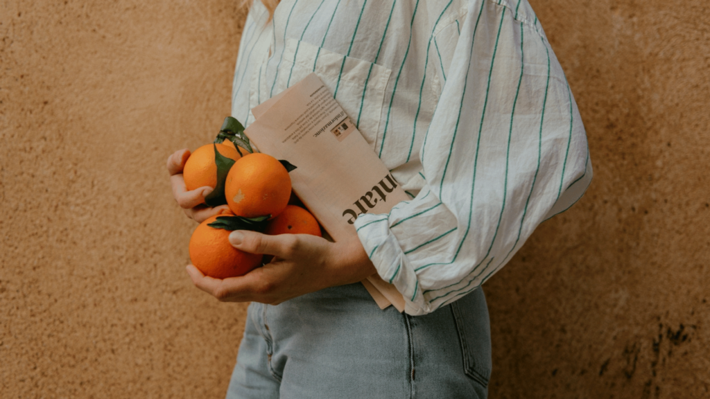 woman balancing oranges and newspaper